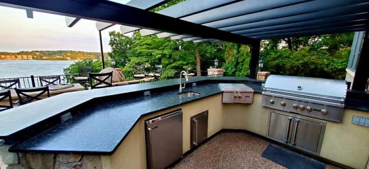 A large outdoor kitchen with a grill and a view of the water.