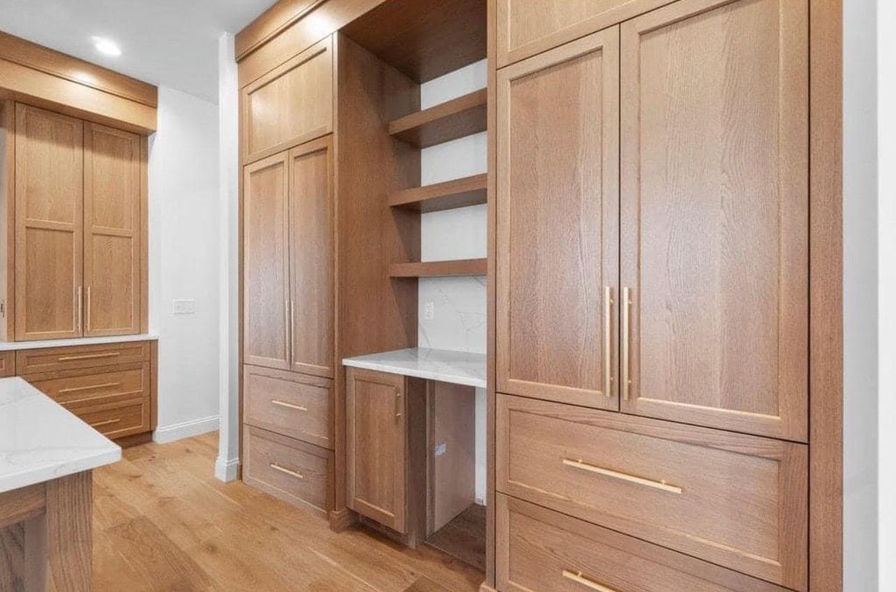 A kitchen with wooden cabinets and drawers and a desk.