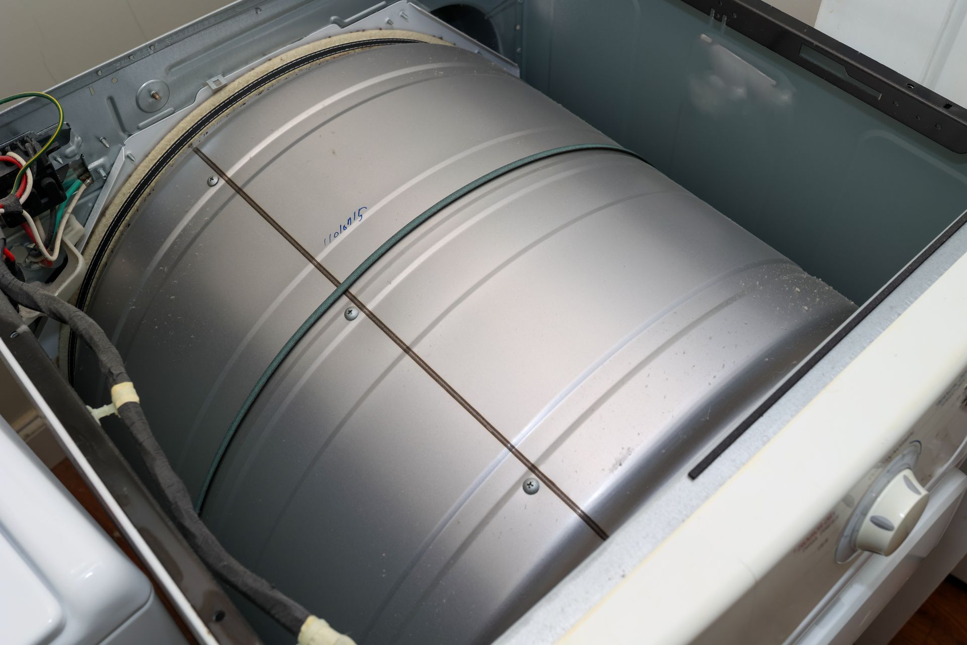 Inside view of a dryer drum with the belt around it, showing the appliance's interior mechanism.