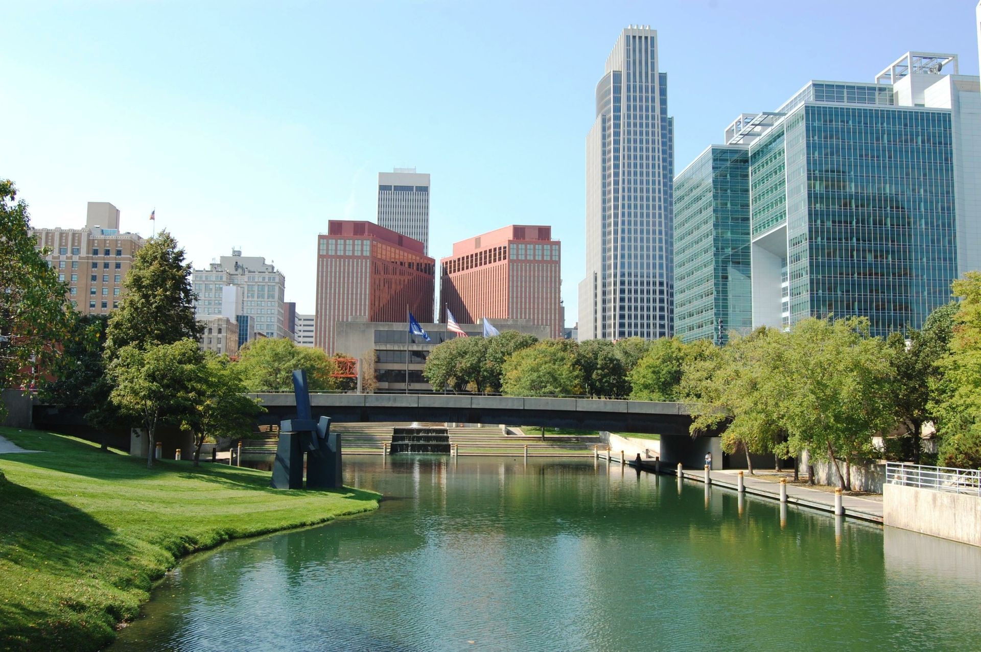 Omaha, Nebraska skyline with buildings, bridge, and a river on a sunny day.