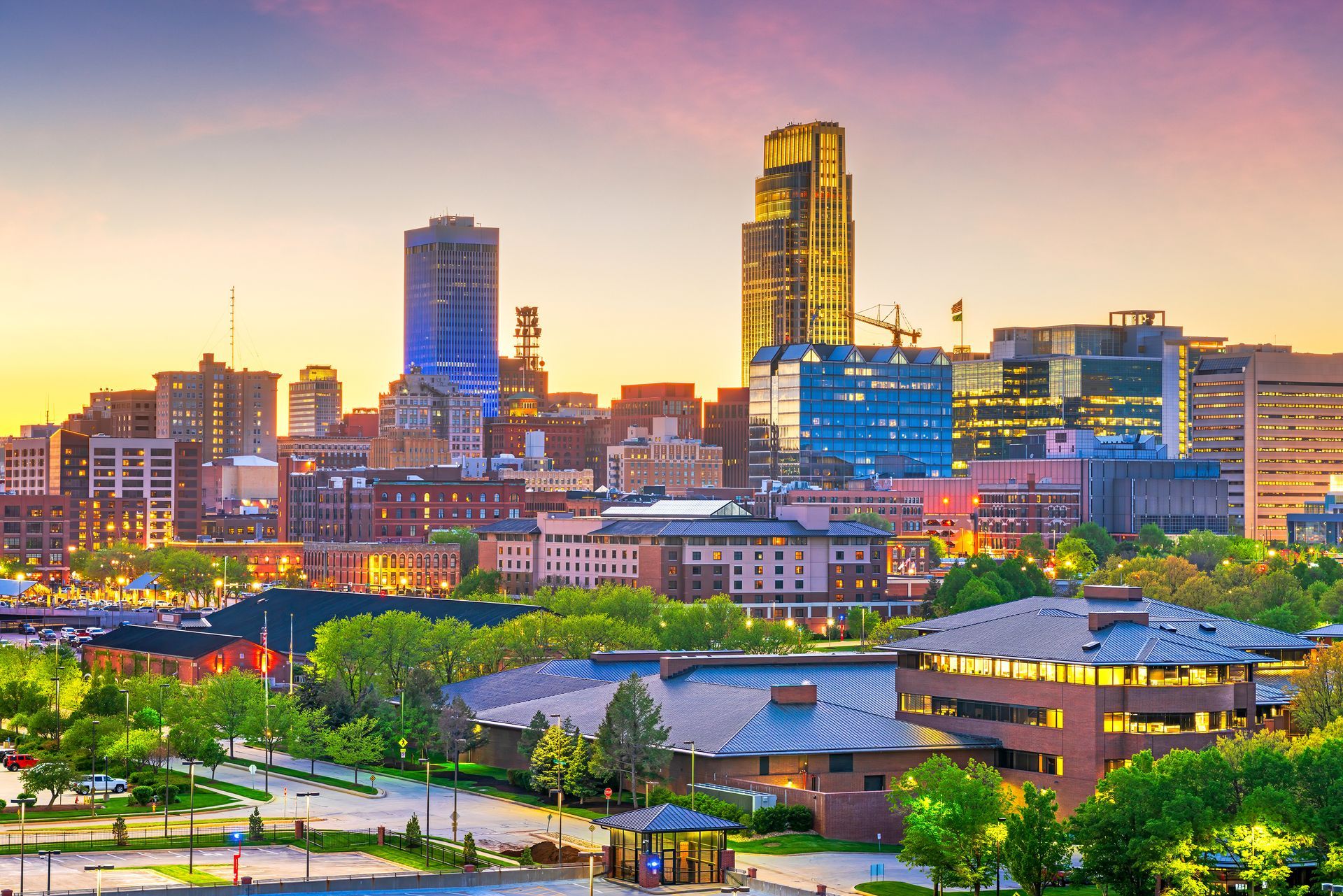 Skyline of Omaha, Nebraska, with modern skyscrapers at dusk, illuminated by warm, golden light.