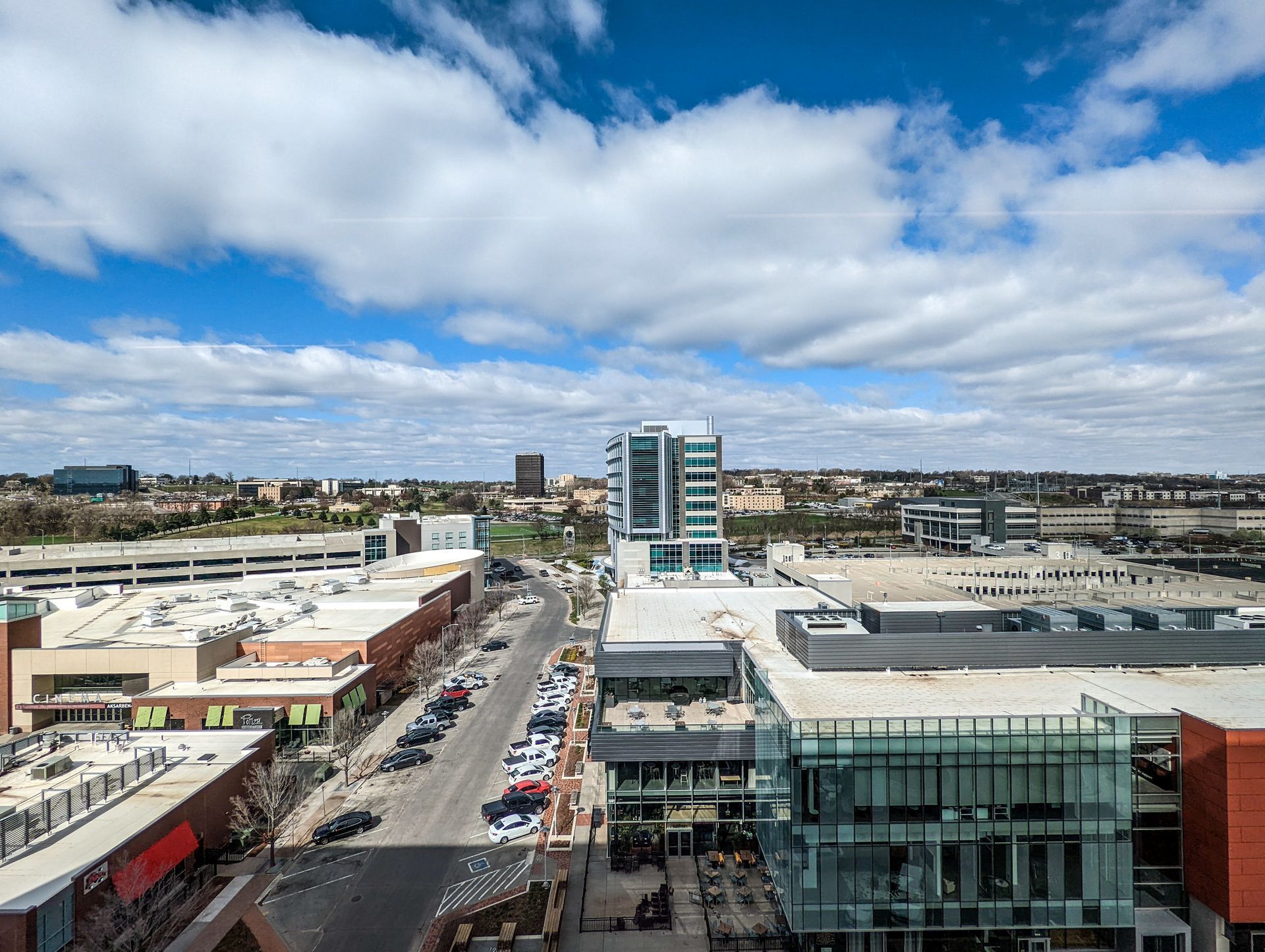 Cityscape with retail and office buildings under a blue sky with fluffy clouds.