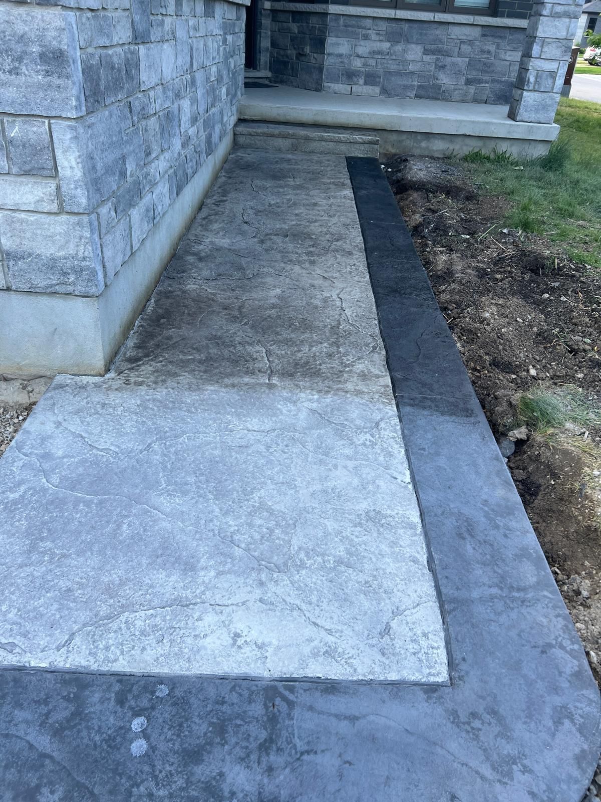 A sidewalk is being built in front of a brick building.