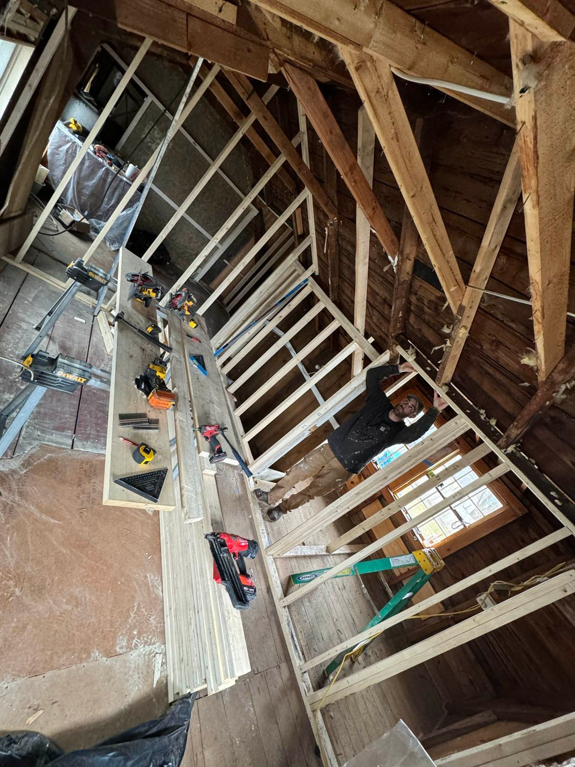 A man is working on a wooden structure in an attic.