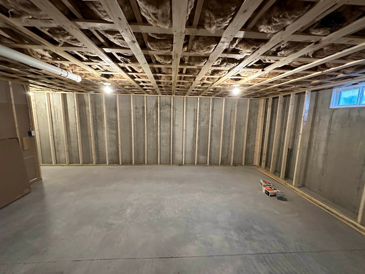 A basement under construction with a wooden ceiling and concrete floor.