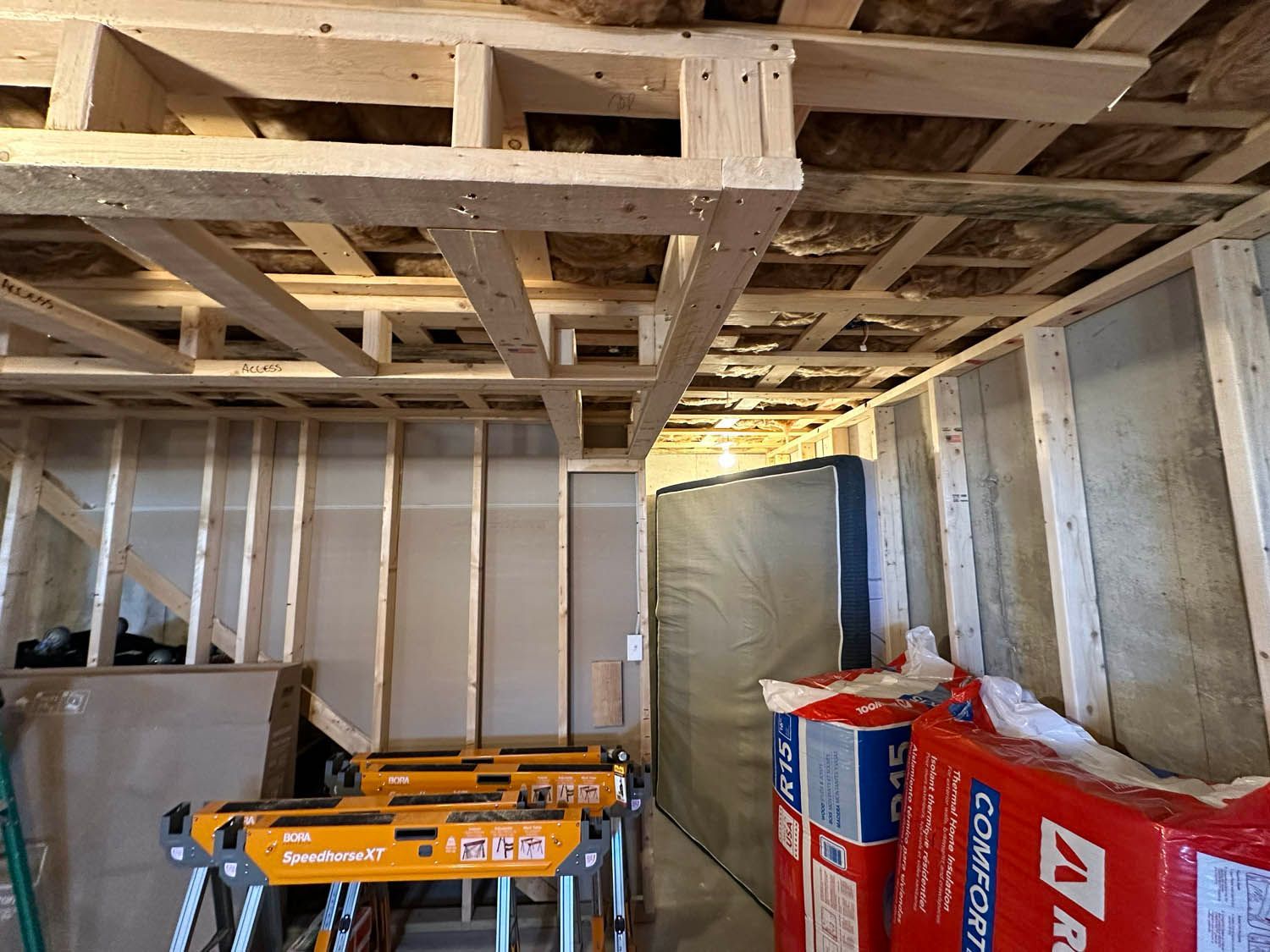 A room with a lot of wooden beams and boxes of insulation.