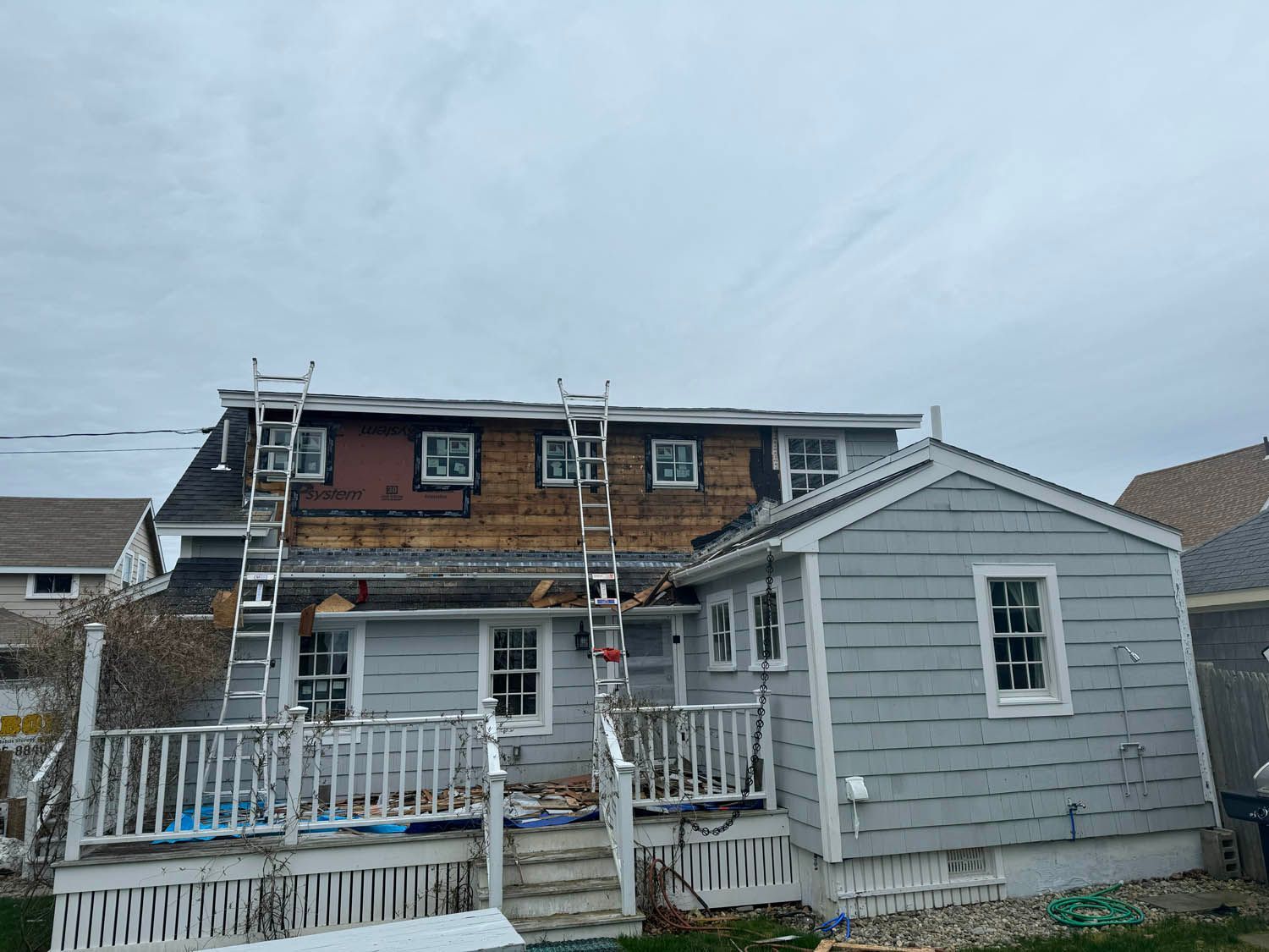 A house with a ladder on the side of it is being painted.