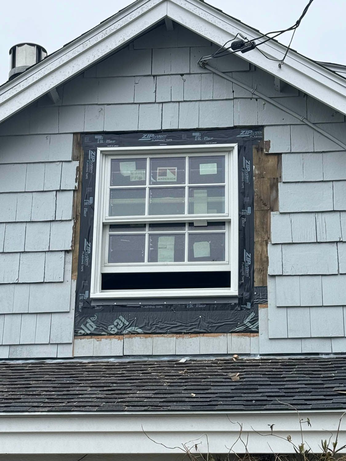 A window is being installed on the side of a house.