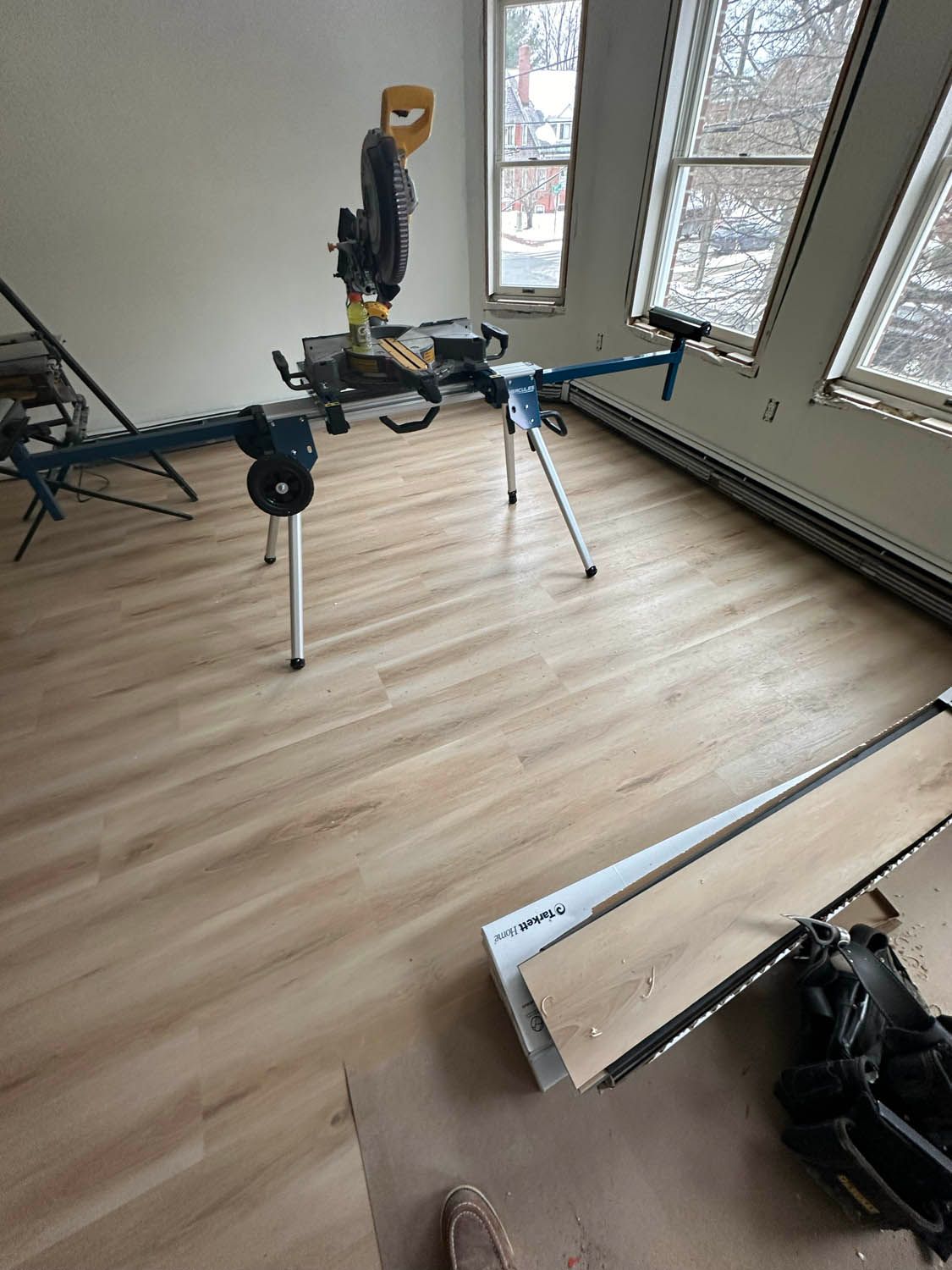 A room with hardwood floors and a circular saw on the floor.