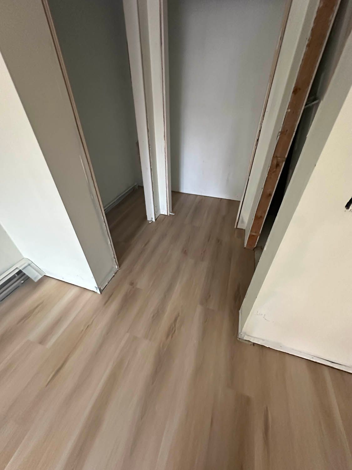 A hallway with wooden floors and white walls in a house.