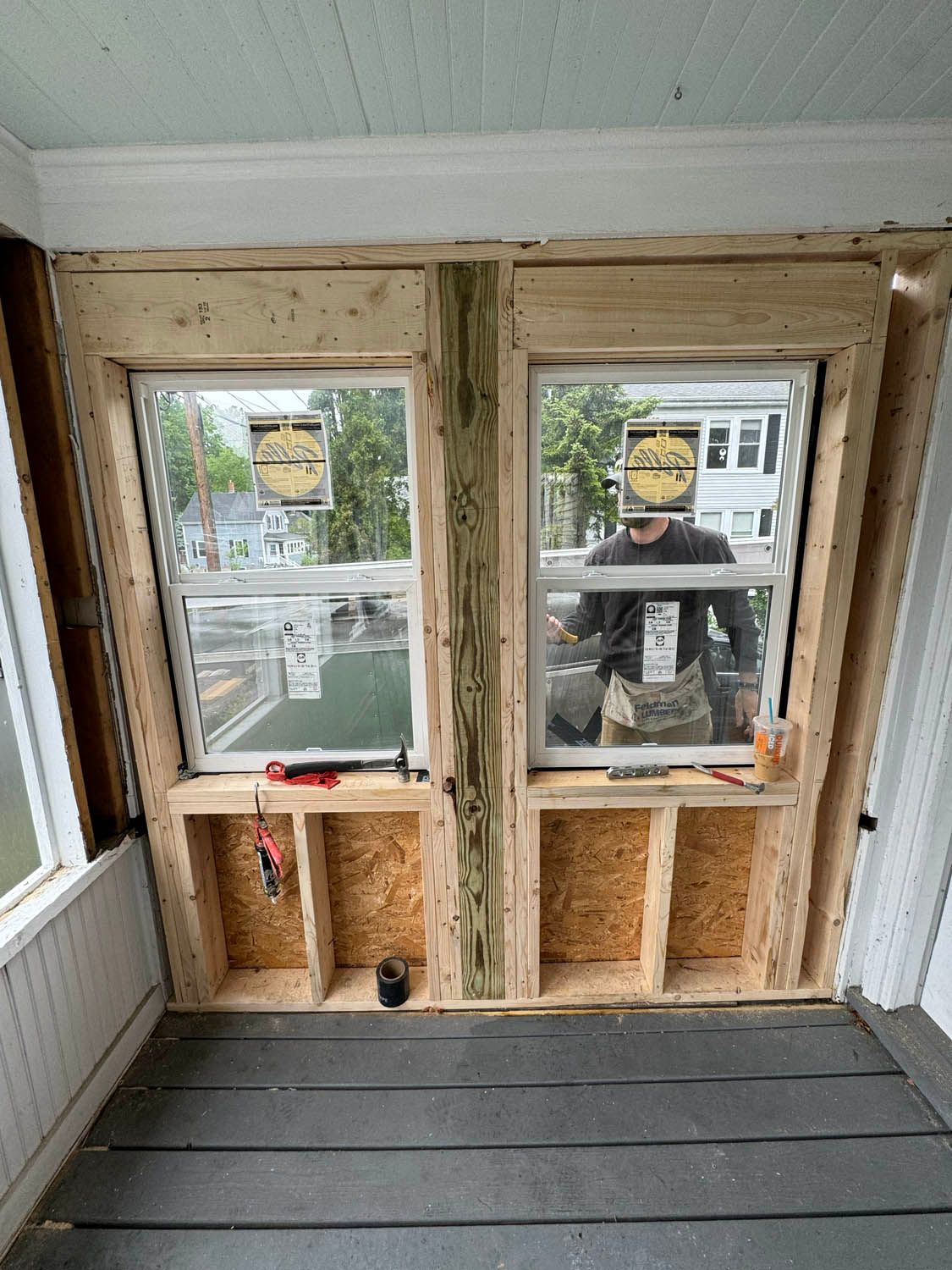 A man is standing in front of two windows in a room.