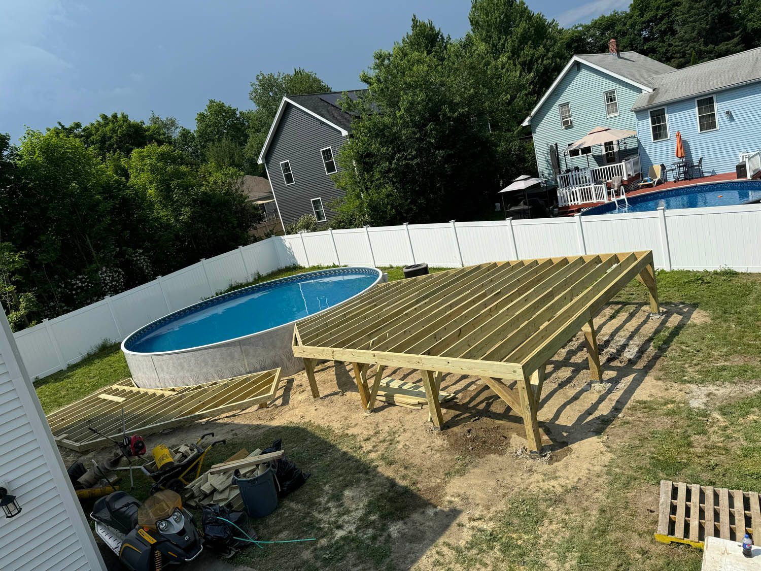 A wooden deck is being built next to a pool in a backyard.