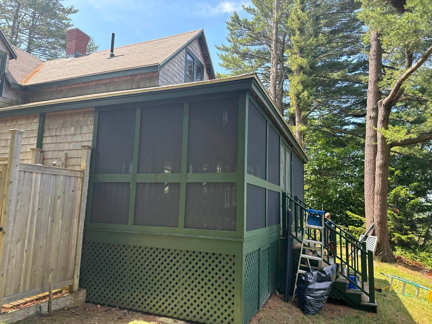A screened in porch with a wooden fence in front of a house.