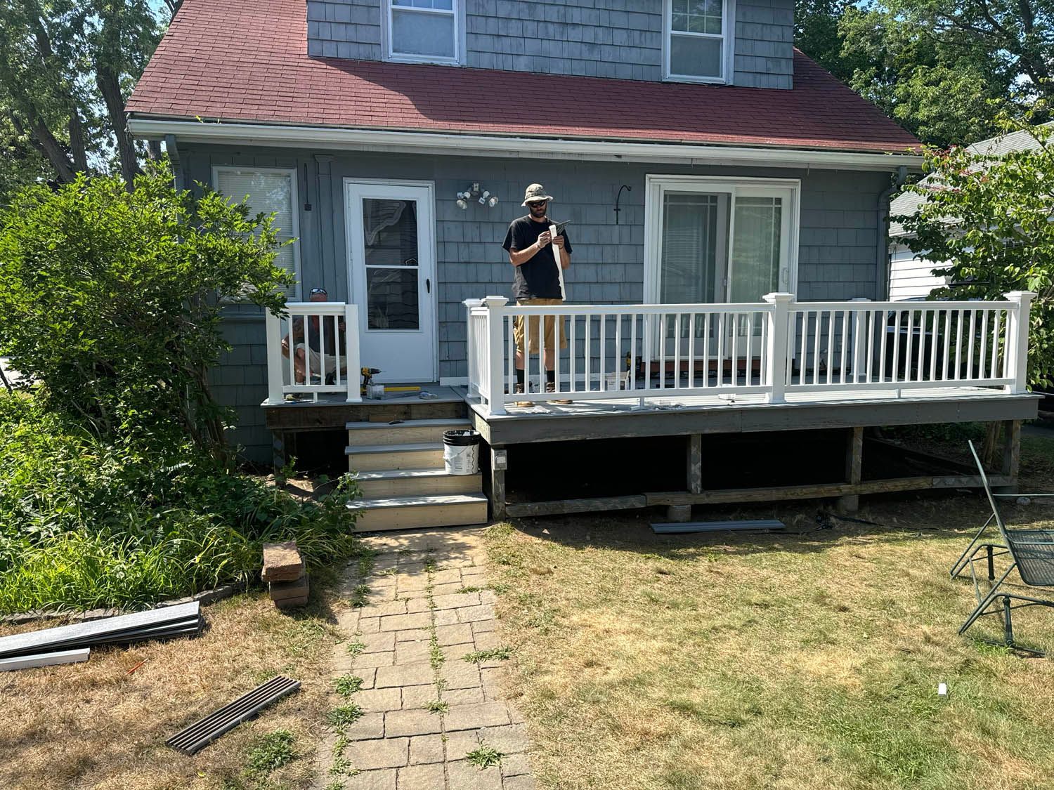 A man is standing on a deck in front of a house.