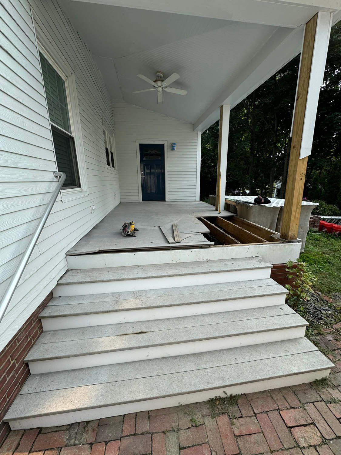 A white house with a porch that is being remodeled.