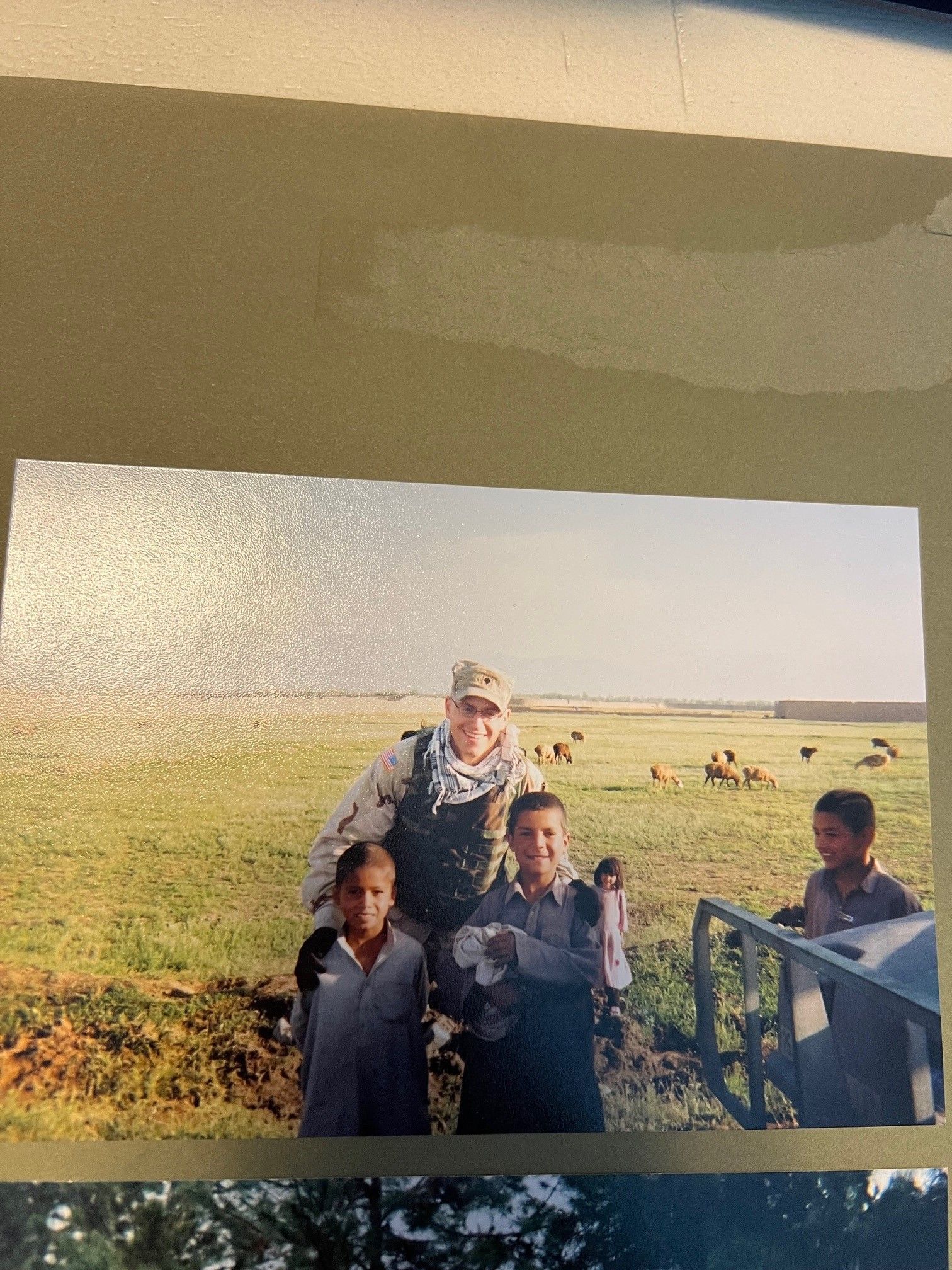 A man in a military uniform is posing for a picture with three children in a field
