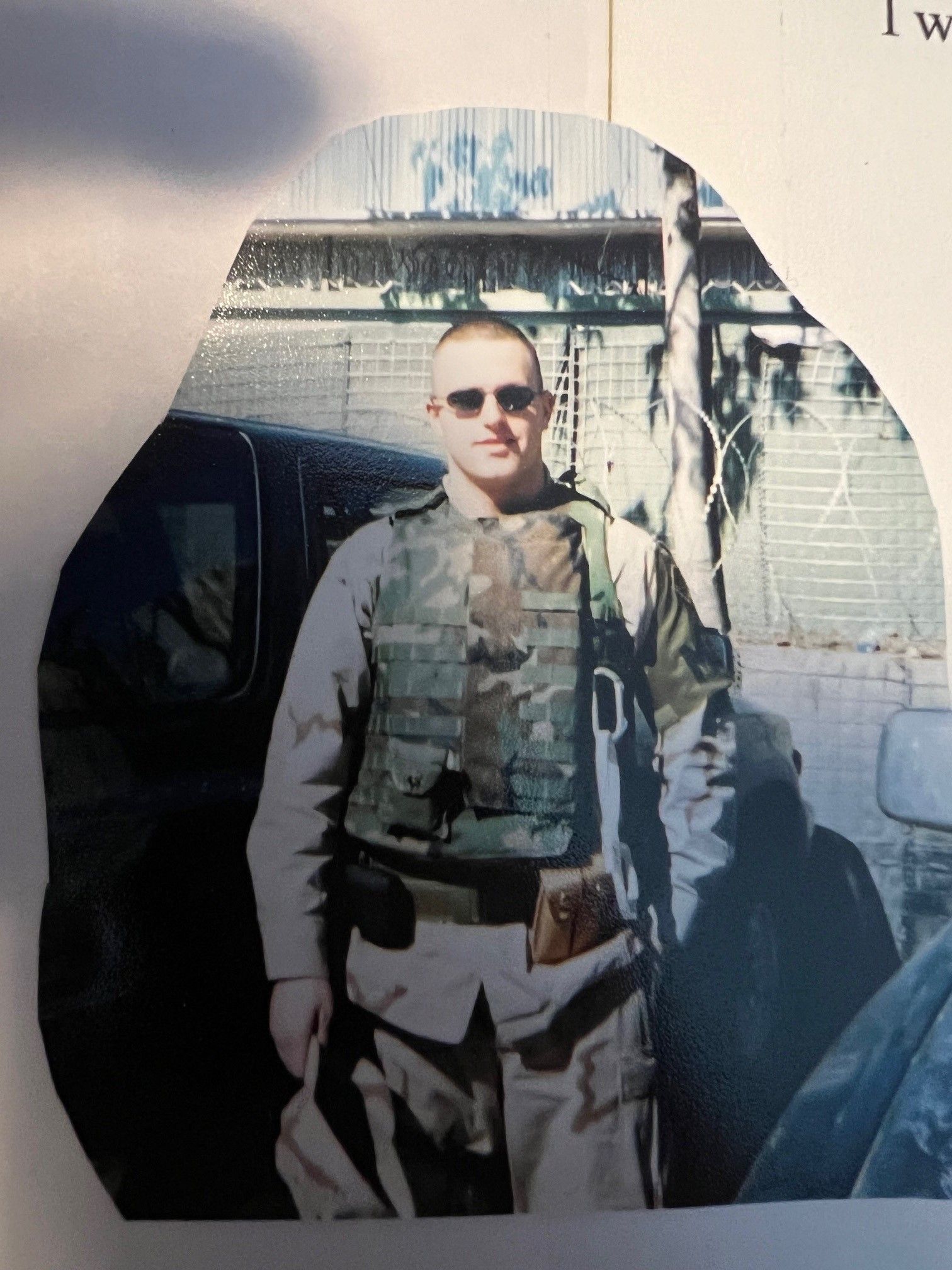 A man in a military uniform is standing in front of a car
