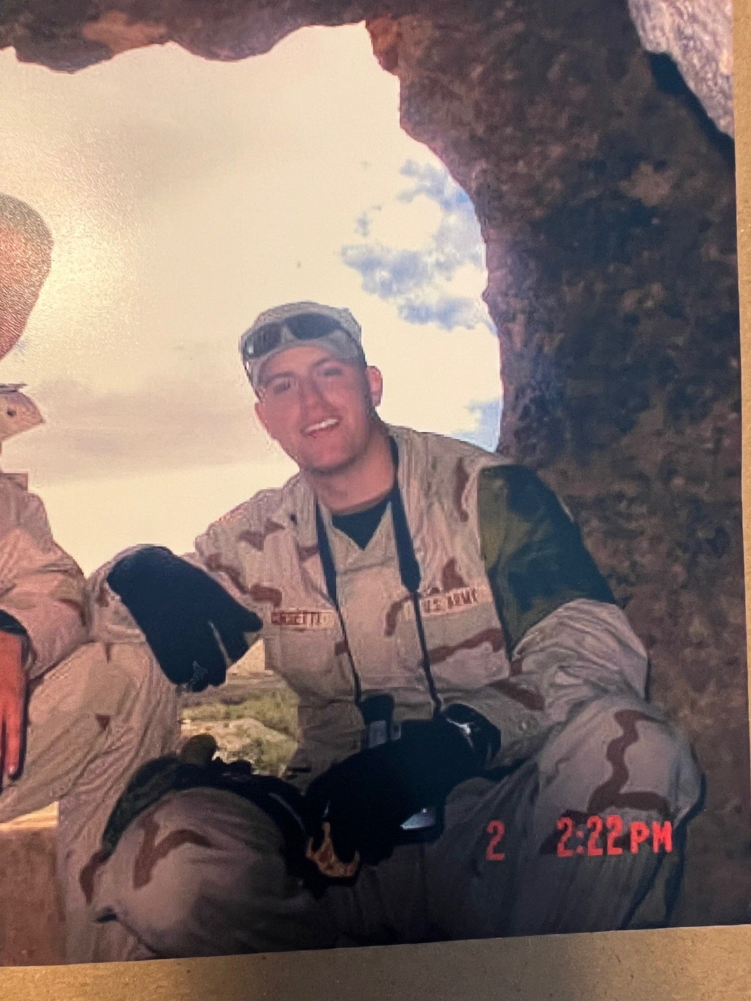 A man in a military uniform is sitting in a cave.