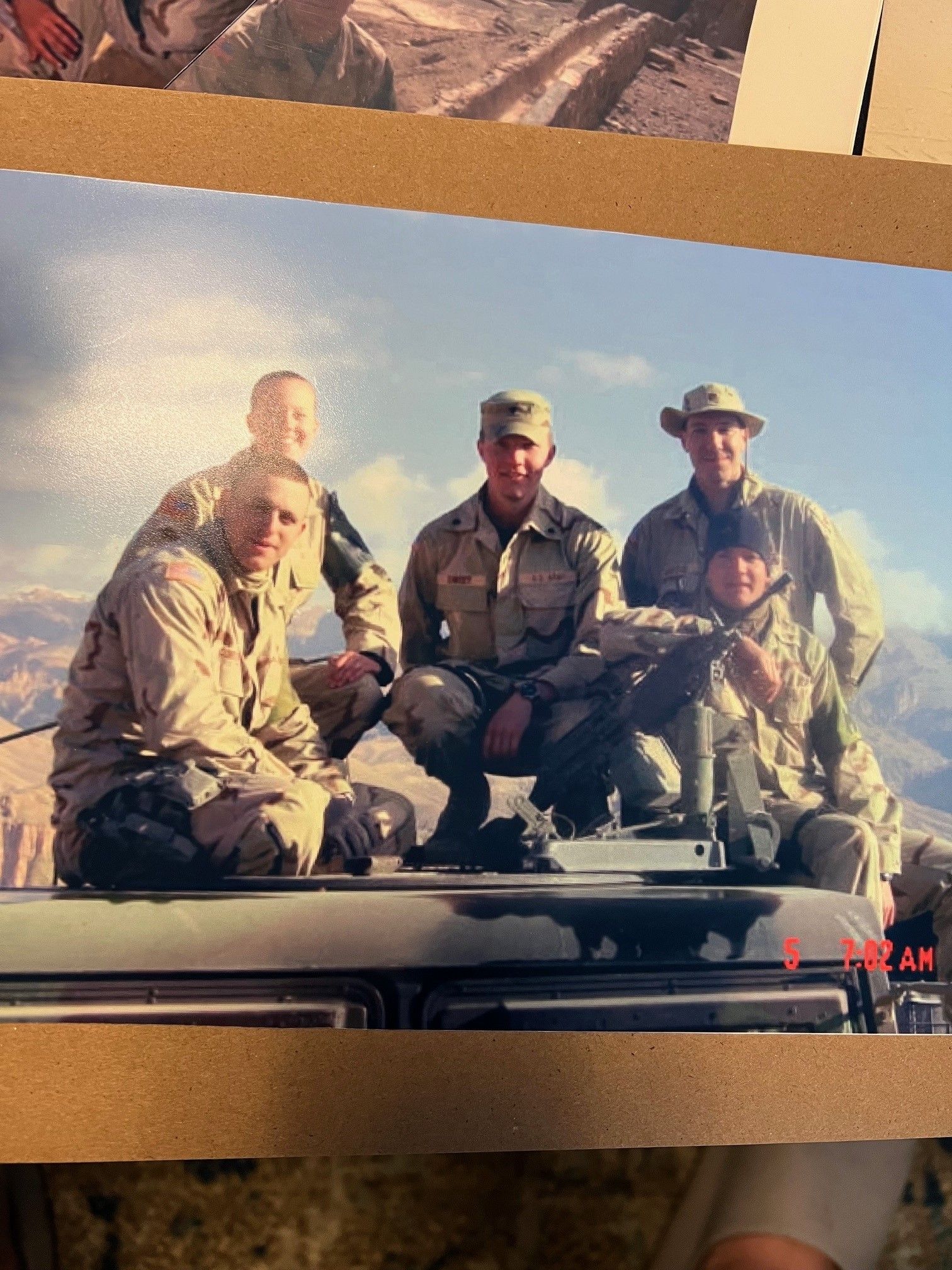 A group of soldiers are posing for a picture on top of a vehicle
