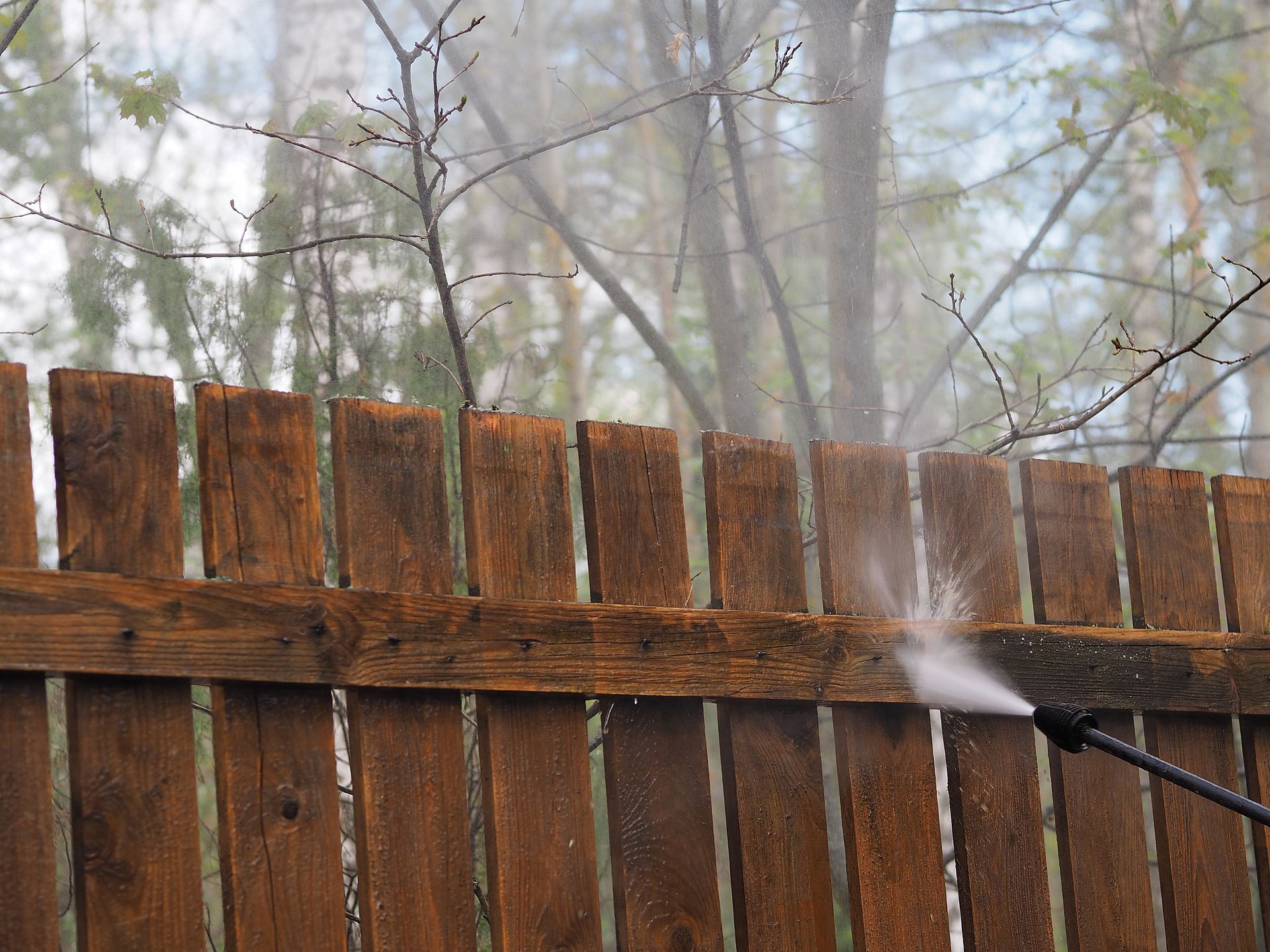 Fence pressure washing process cleaning grime and buildup from wooden fence surface.