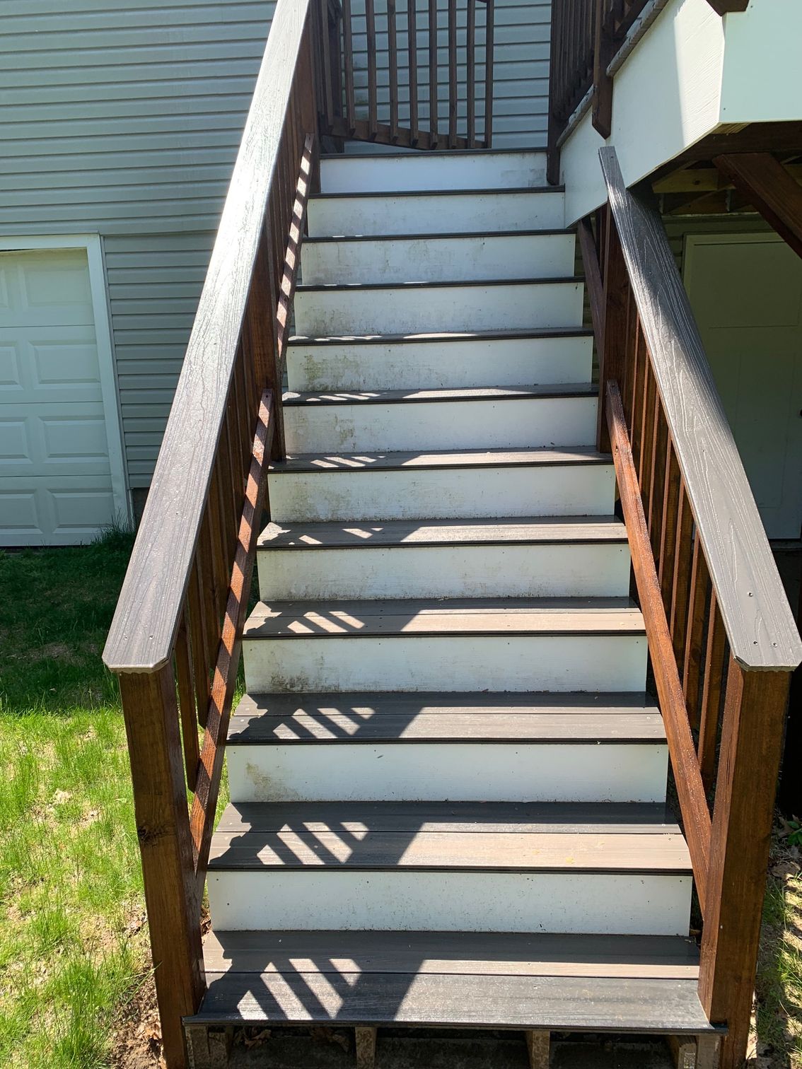 Outdoor wooden staircase with brown railings and light gray steps.