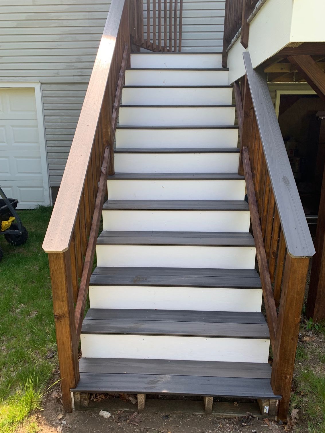 Wooden outdoor stairs with dark brown railings and grey/white treads.