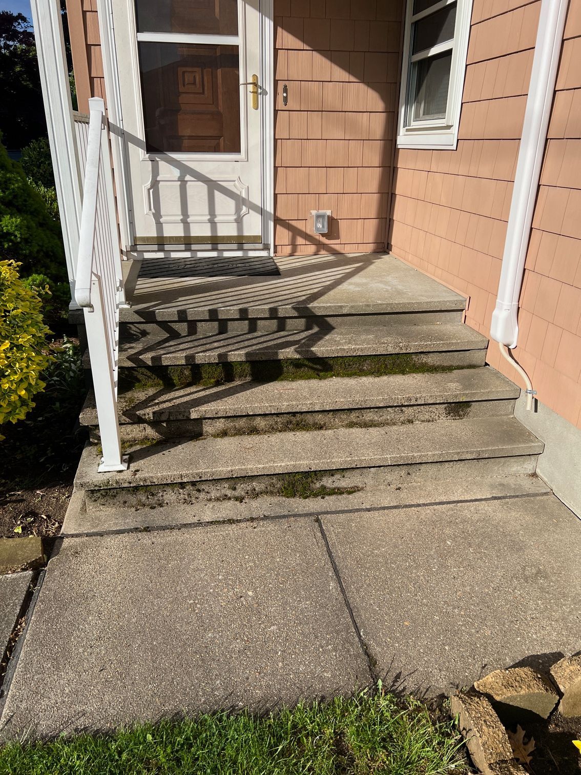 A concrete porch with stairs leading up to the front door of a house.