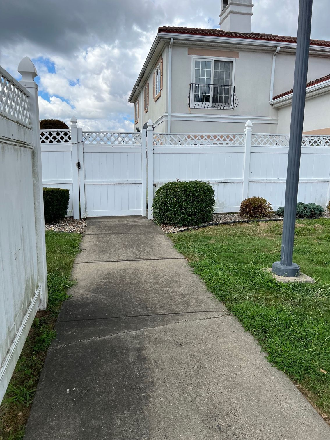 A walkway leading to a house with a white fence and a gate.
