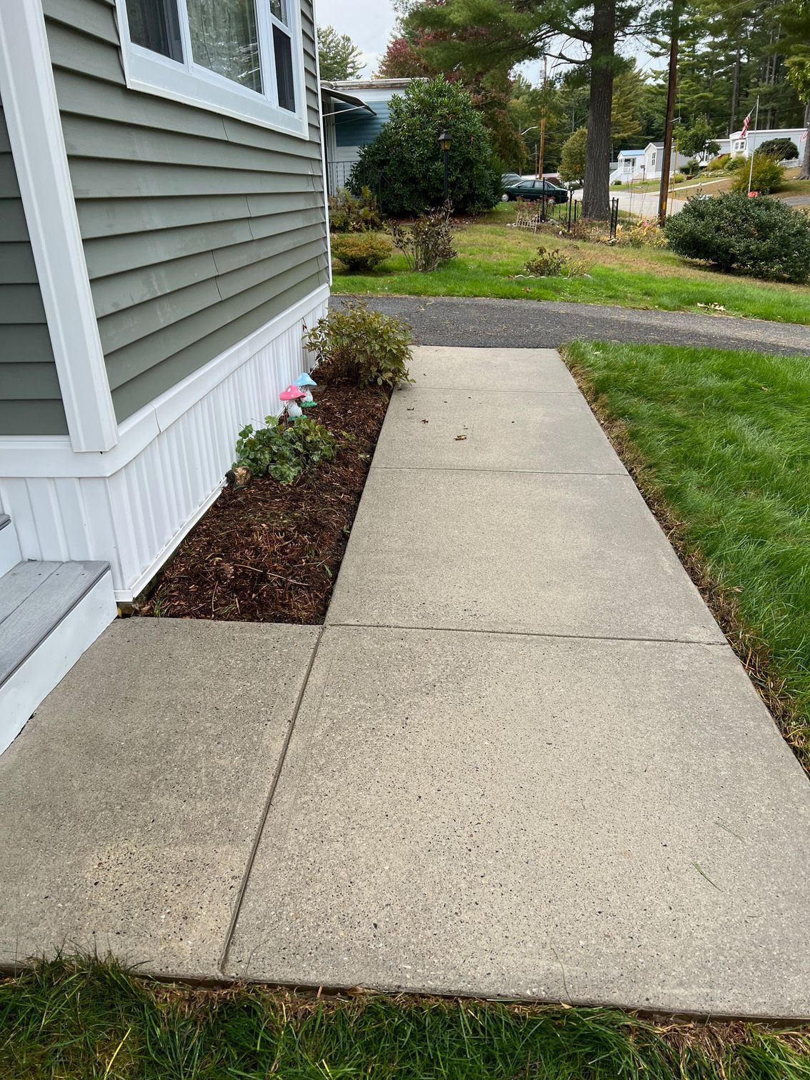 A sidewalk leading to a house with a concrete walkway.