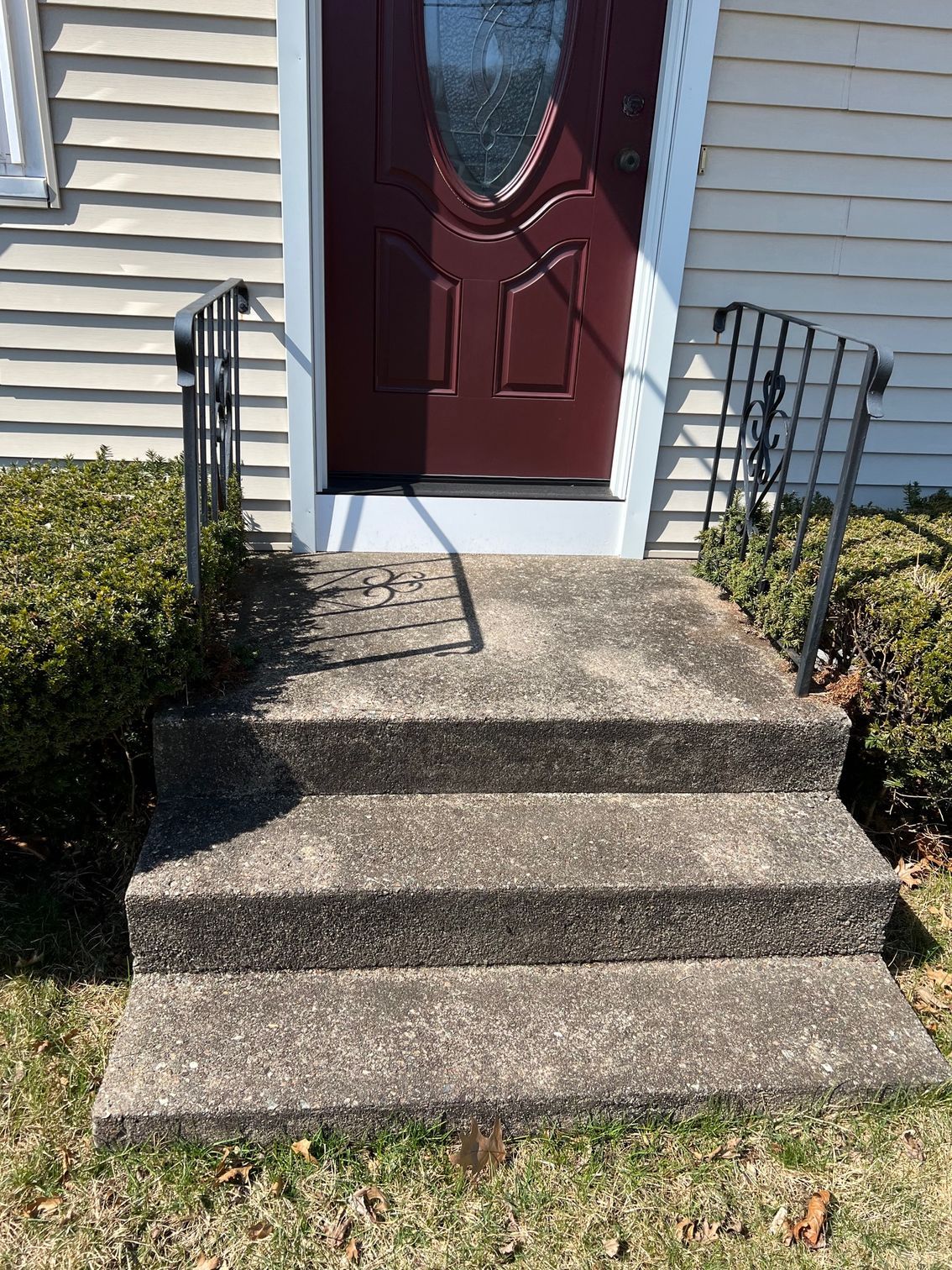 A set of concrete steps leading up to a red door of a house.