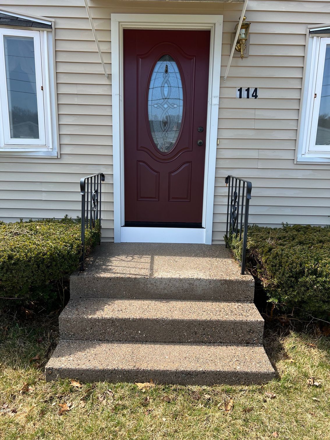 The front door of a house with a red door and steps leading up to it.