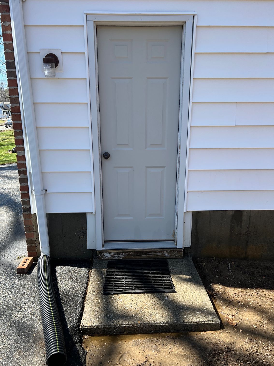 A white door is on the side of a white house.