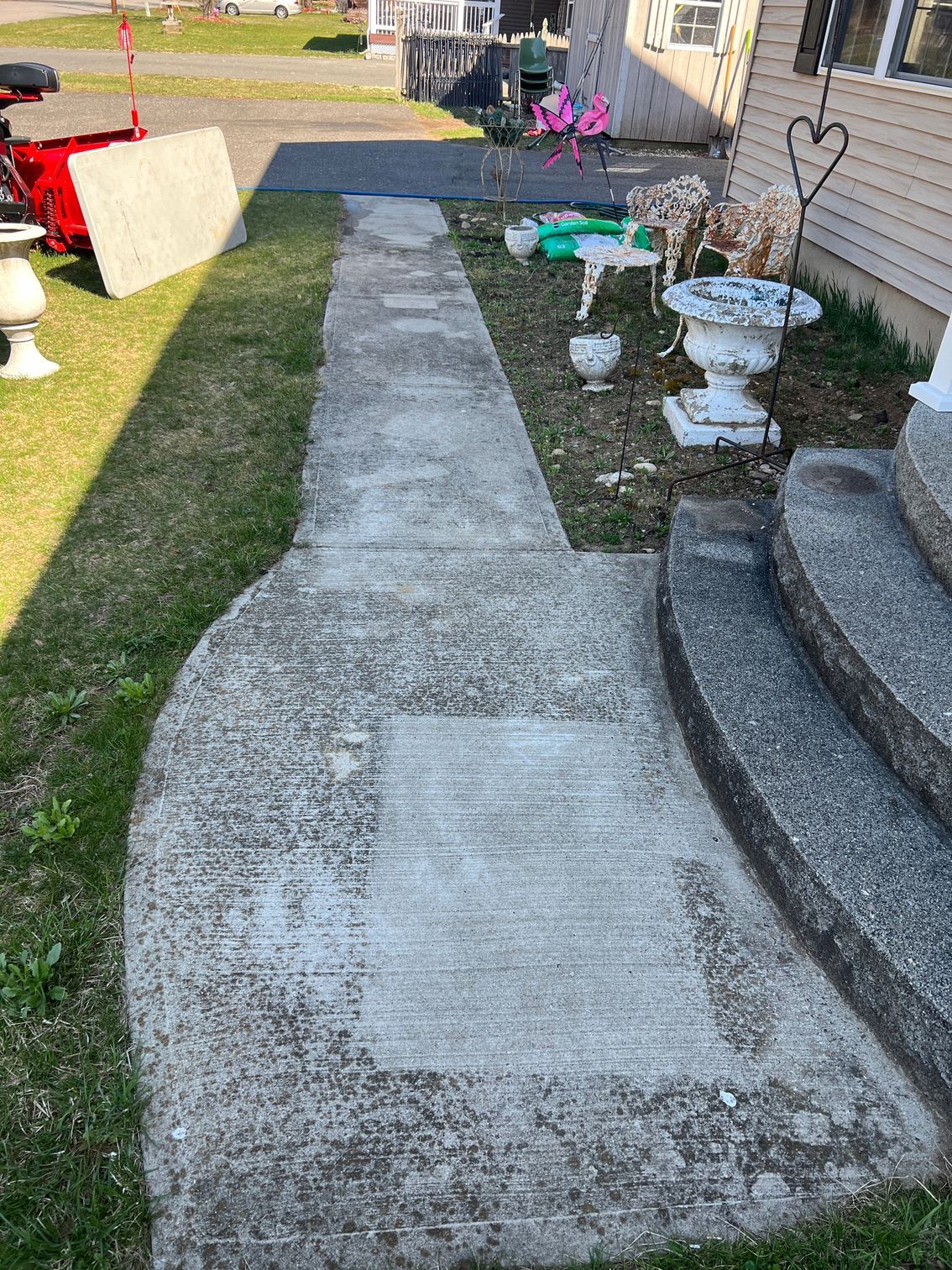 Concrete walkway leading to house entrance with decorative items.