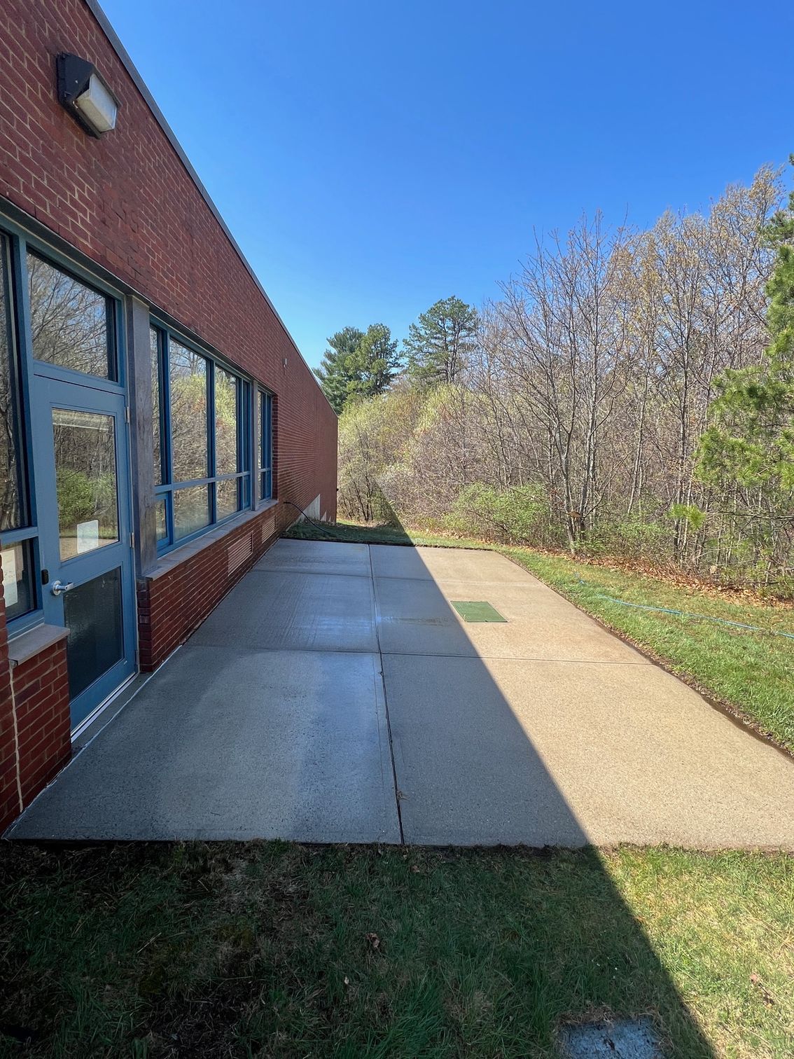 A sidewalk leading to a brick building with trees in the background.