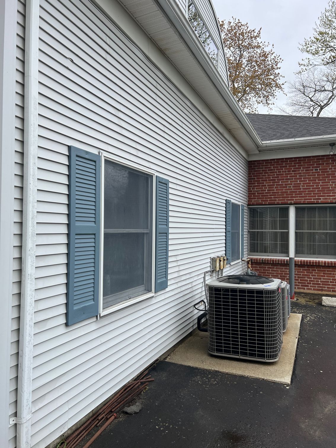 A white house with blue shutters and a black air conditioner