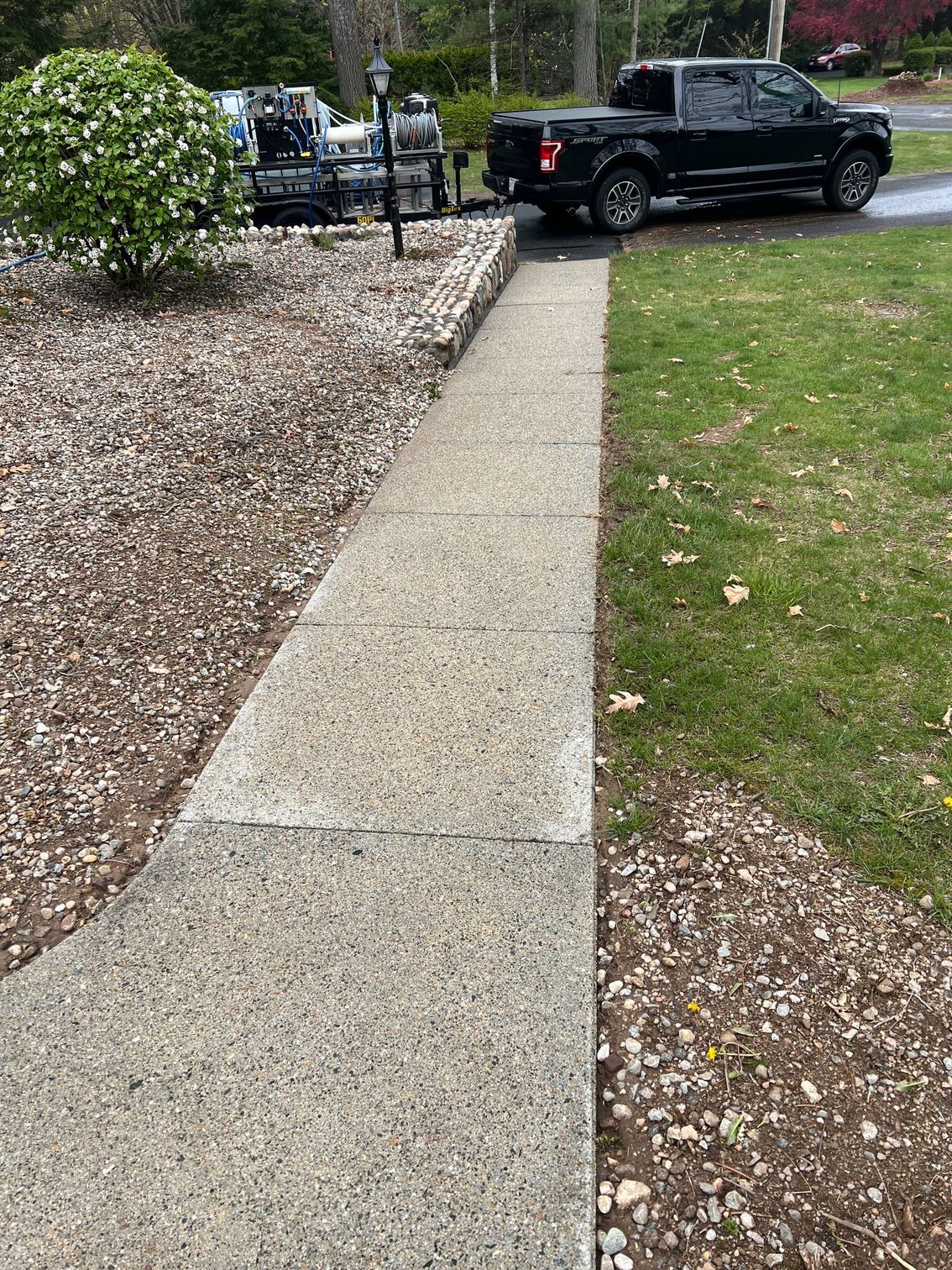 A black truck is parked on the side of a sidewalk.