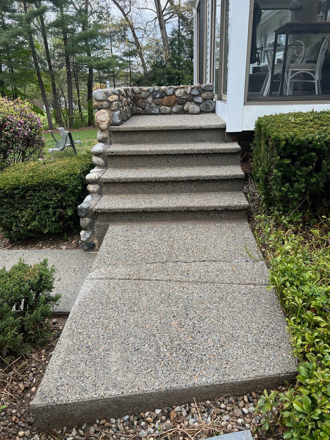 A concrete walkway with stairs leading up to a house.