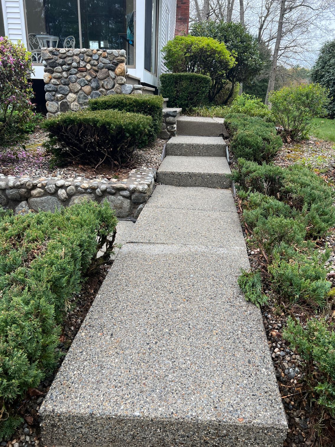 A concrete walkway with stairs leading up to a house.