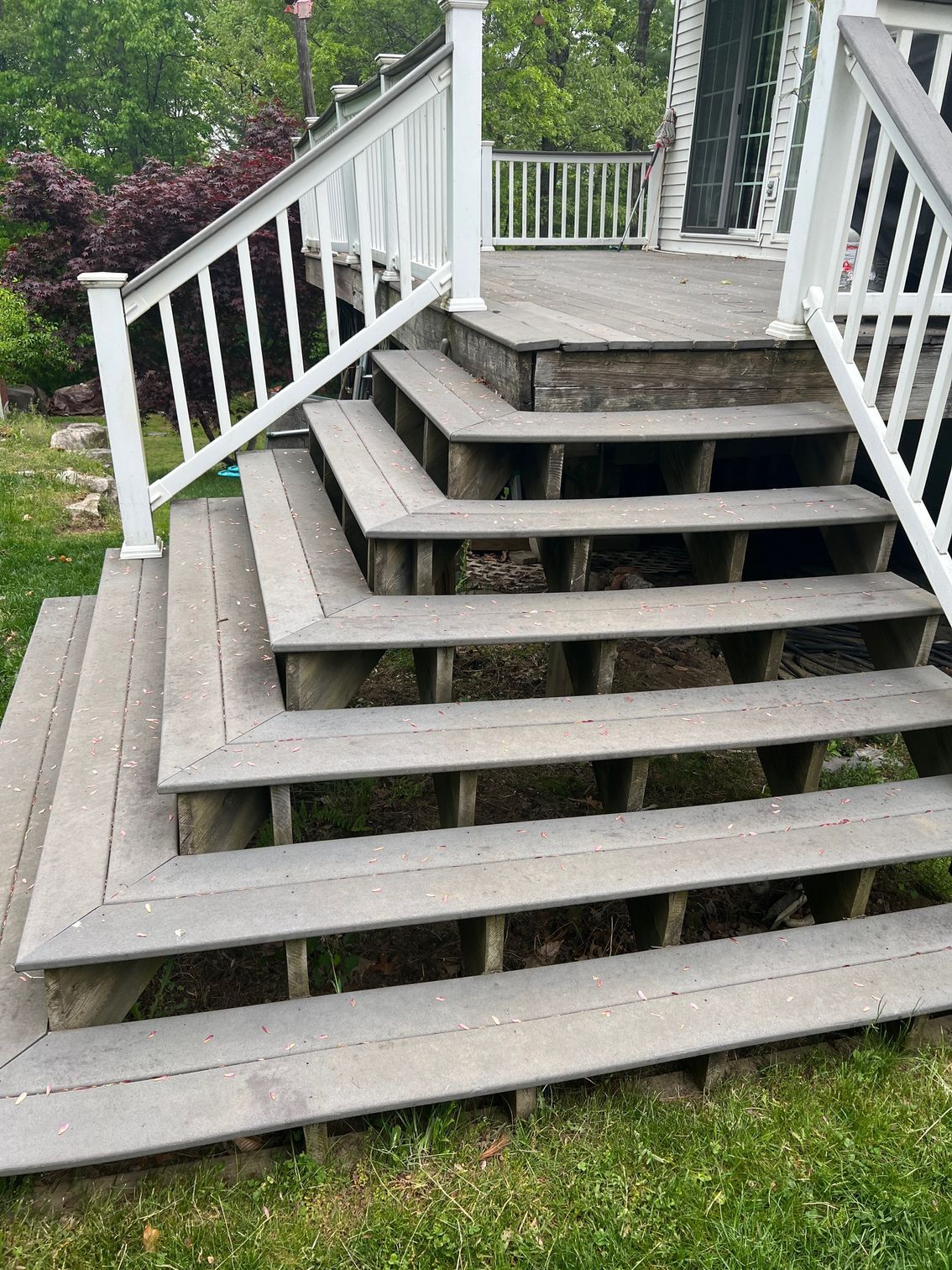 Outdoor deck with multiple gray steps and white railings.
