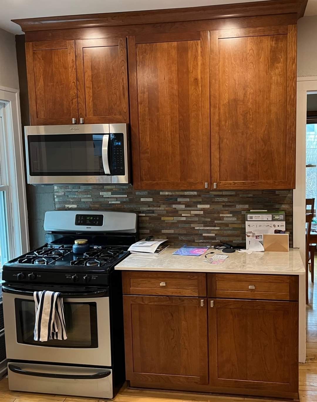 Kitchen with stainless steel stove, microwave, and brown cabinets. Counter with backsplash.