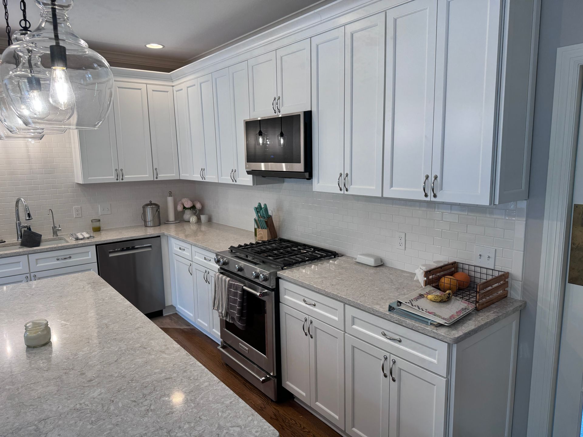White kitchen with white cabinets, light countertops, and stainless steel appliances.