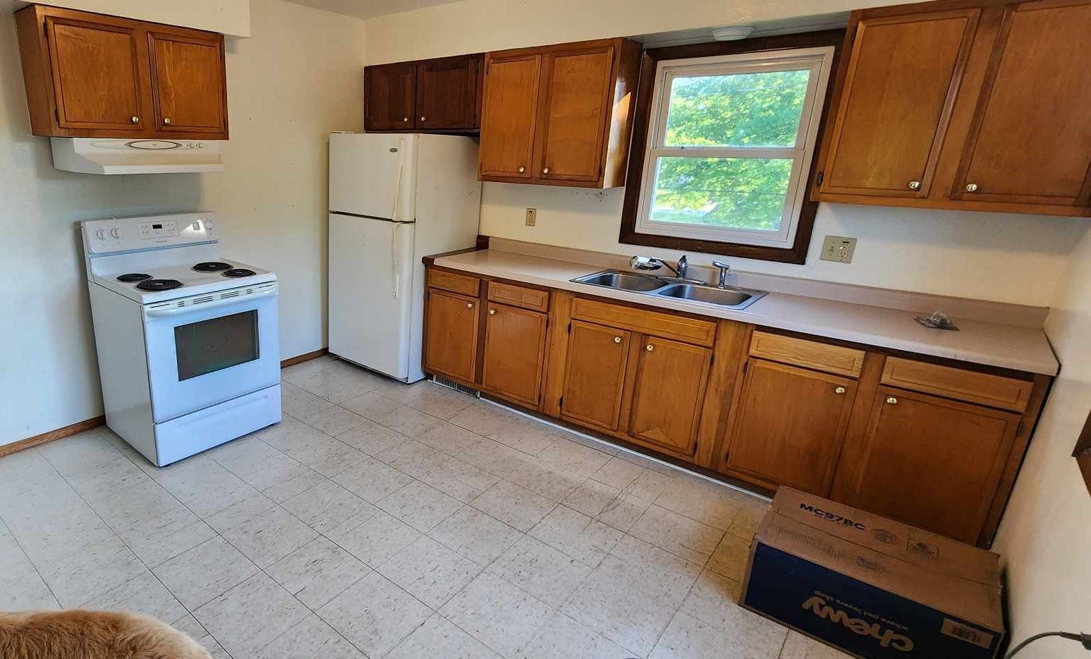 Kitchen with light-colored cabinets, white appliances, and a window.