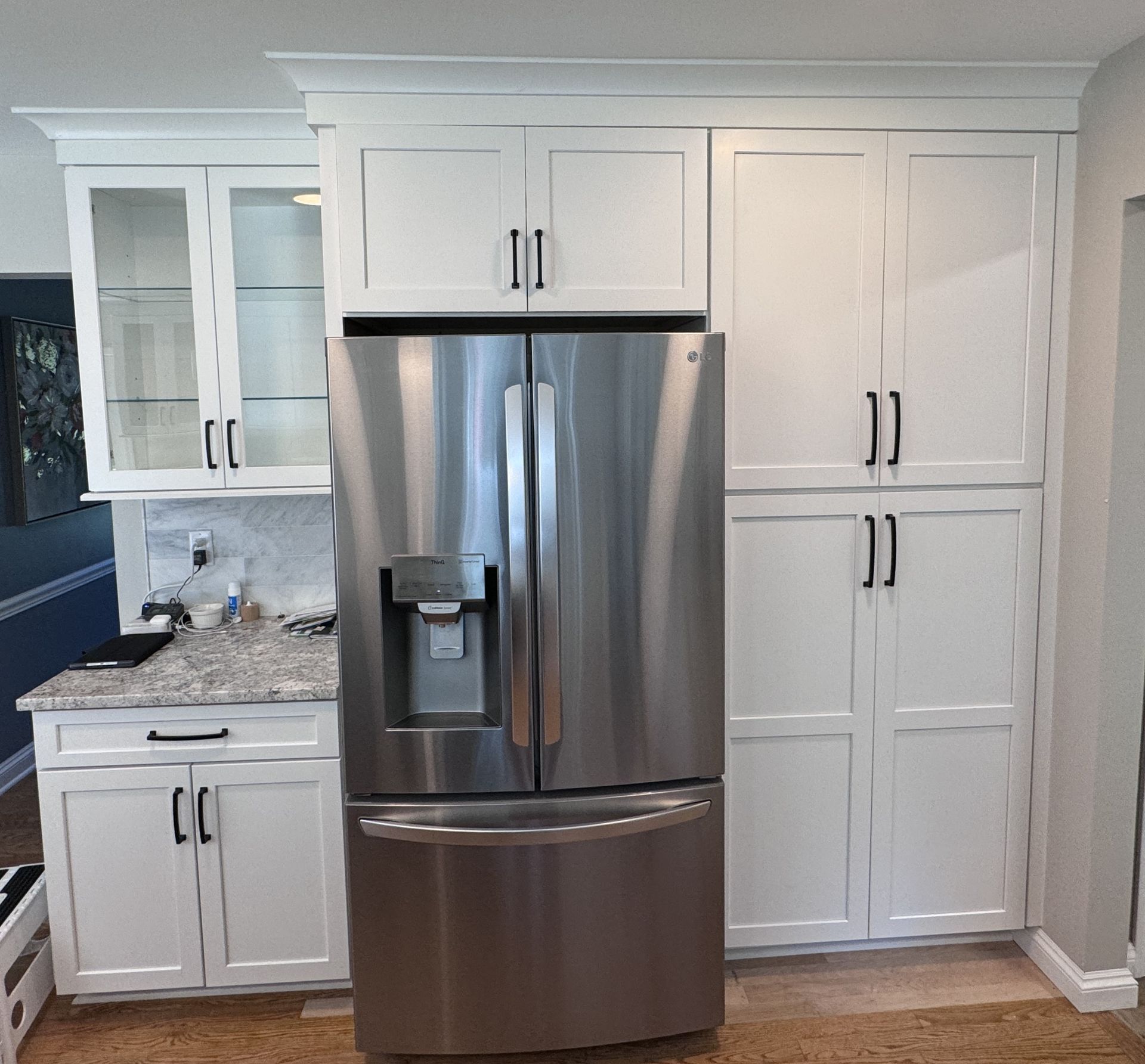 White kitchen cabinets frame a stainless steel refrigerator.