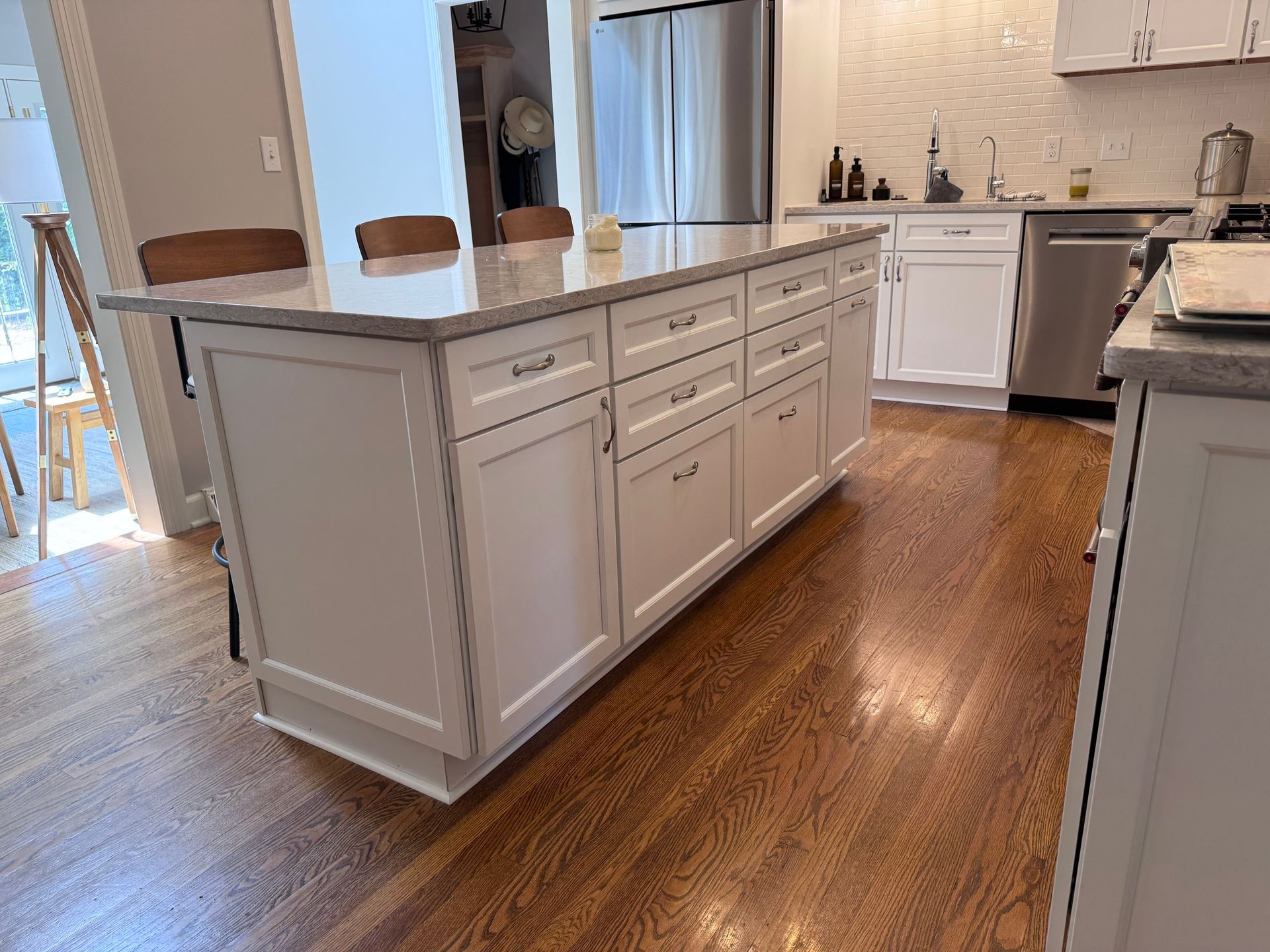 White kitchen island with granite countertop and hardwood floor.