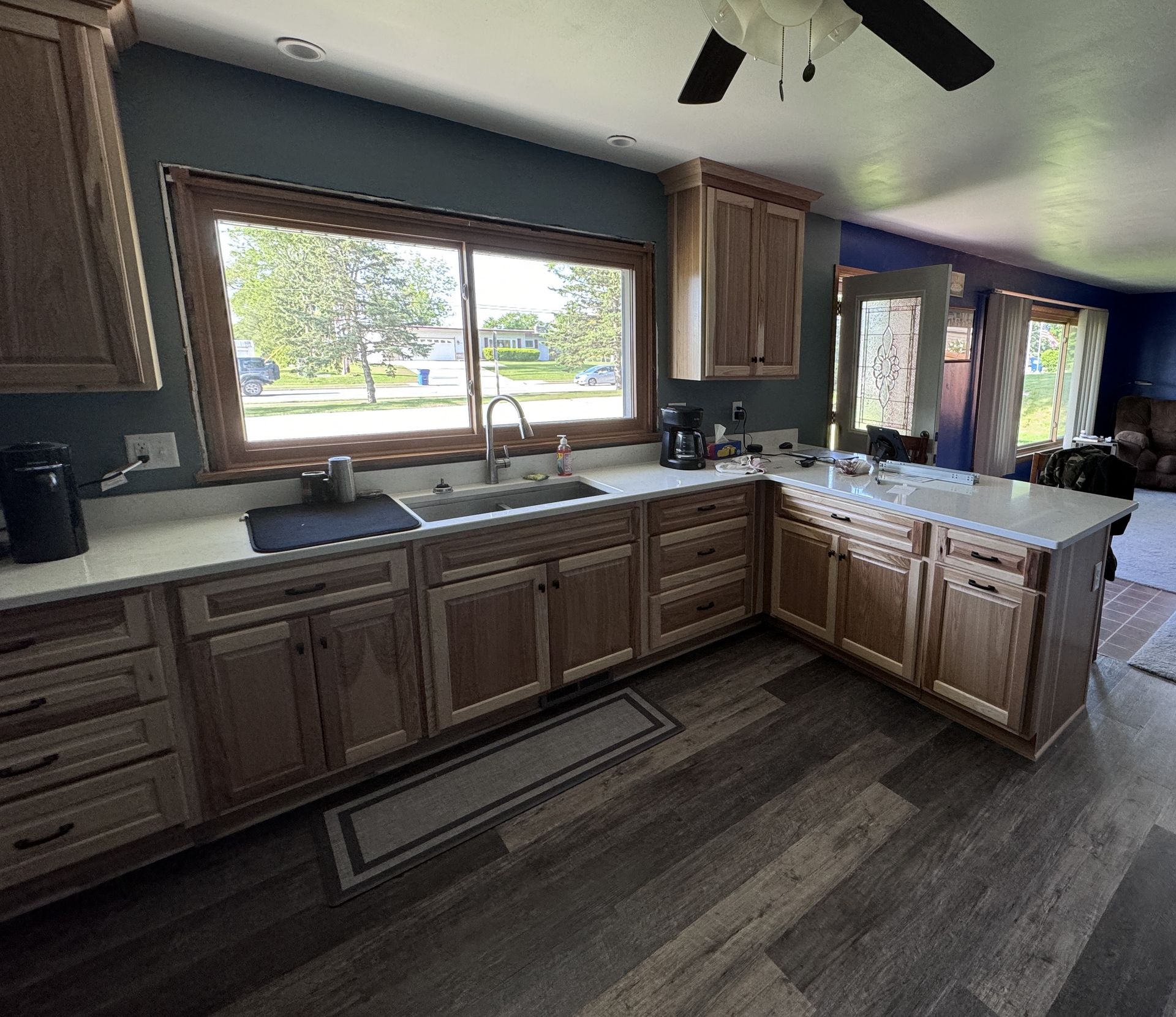 Kitchen with light wood cabinets, white countertops, and a large window.