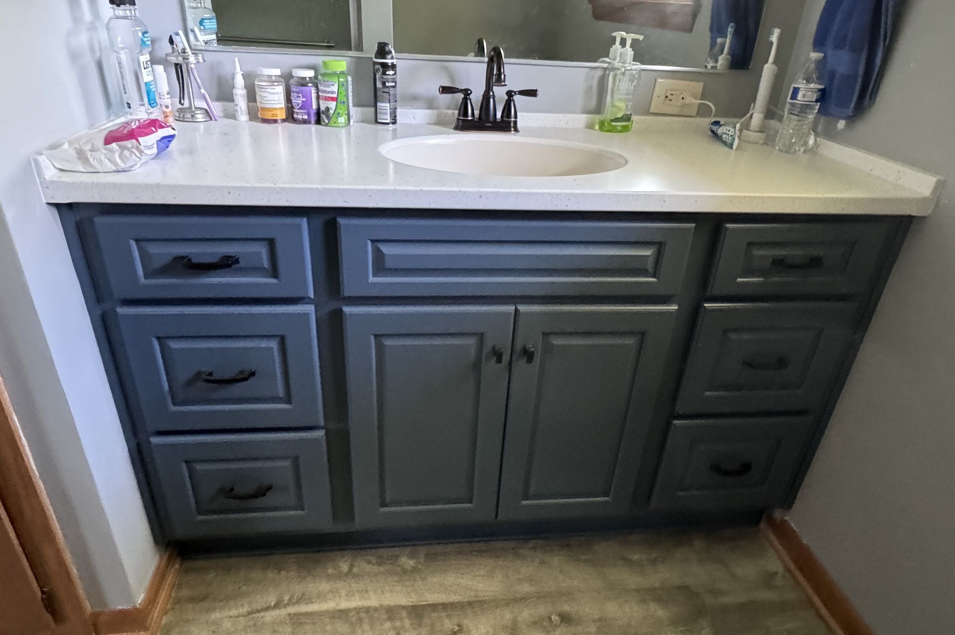 Bathroom vanity with gray cabinets, white countertop, and dark faucet.