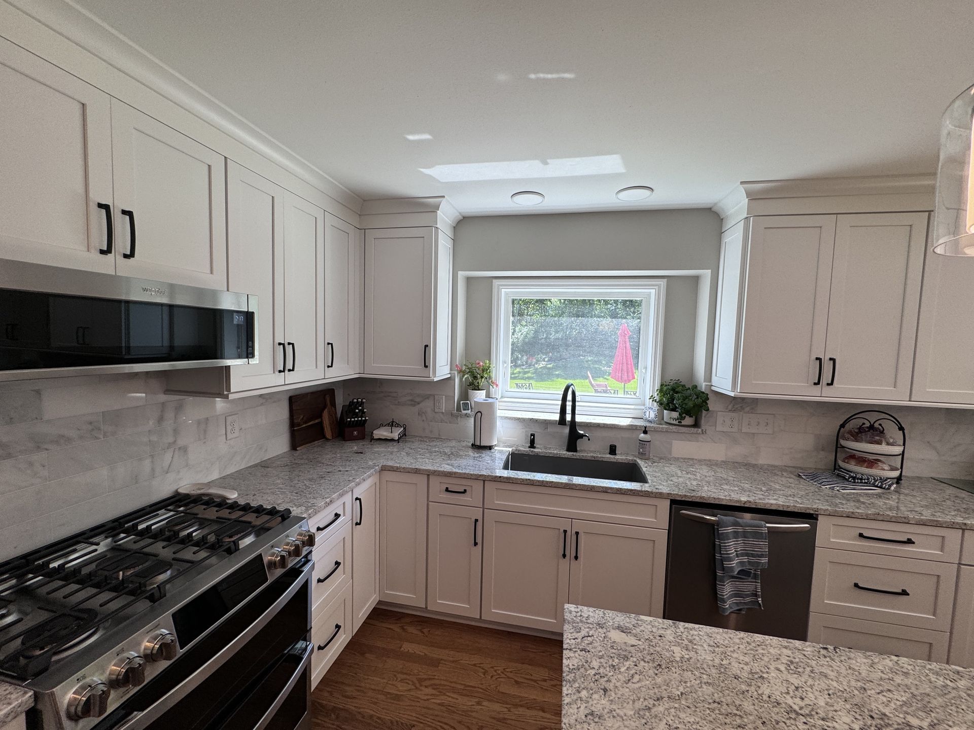 White kitchen with granite countertops, stainless steel appliances, and black hardware.