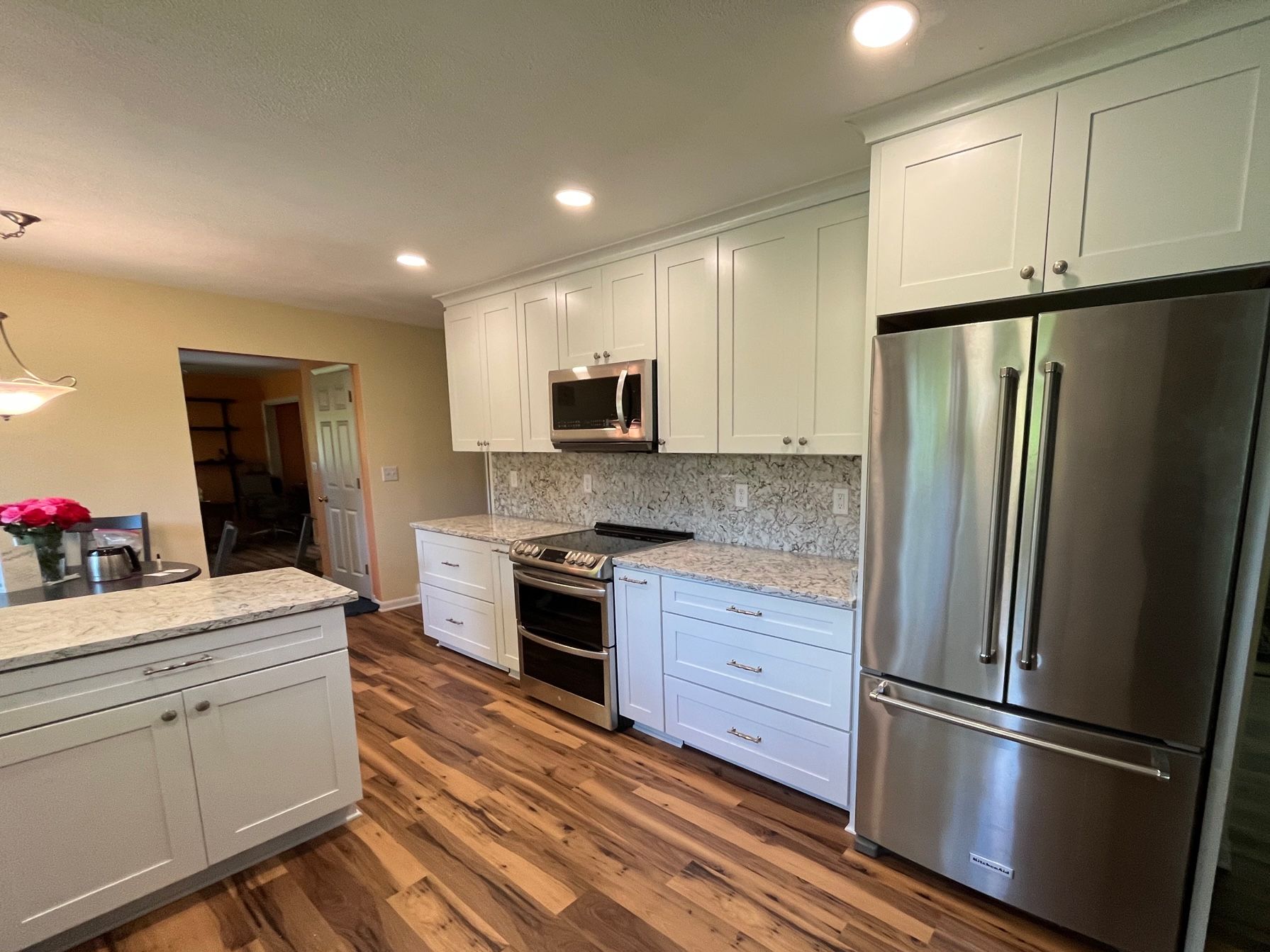Kitchen with light blue cabinets, stainless steel appliances, granite countertops, and wood flooring.
