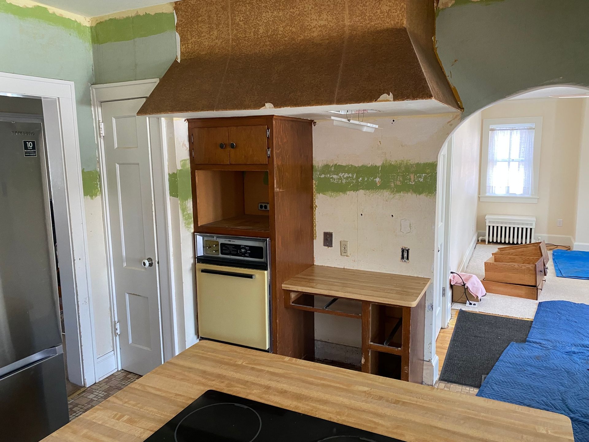 Kitchen undergoing renovation with wooden cabinetry, oven, and countertop. Green and tan walls.