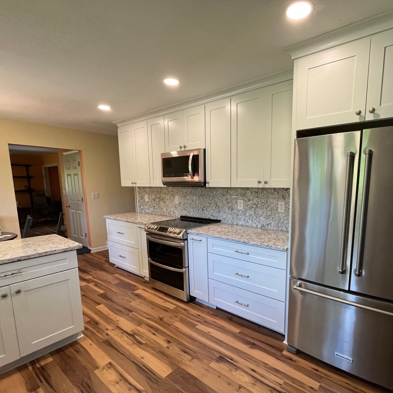 Newly renovated kitchen with white cabinets, stainless steel appliances, granite countertops, and wood-look flooring.